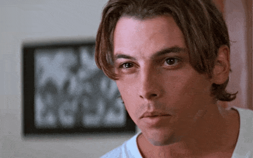 a man with long hair is looking at the camera