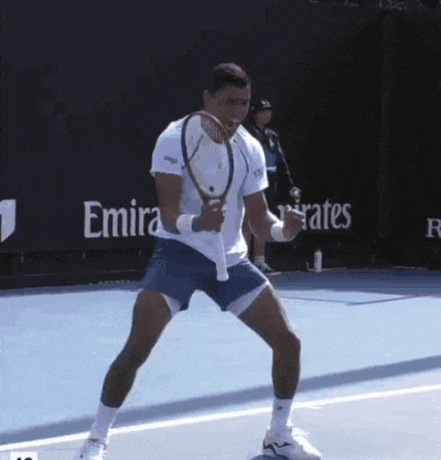a man holding a tennis racquet on a tennis court in front of emirates advertisements