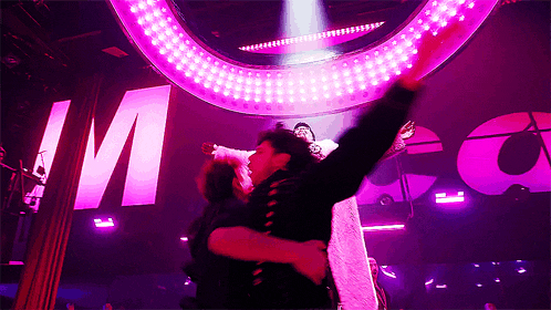 a man holds a woman in his arms in front of a sign that says mcca