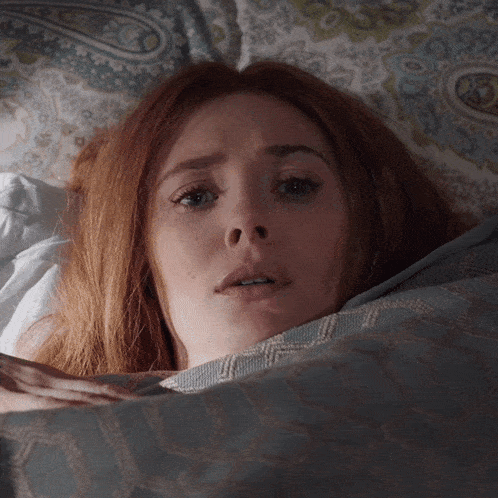 a woman with red hair is laying in bed