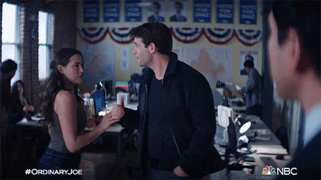 a man and a woman are standing in front of a wall with posters for ordinary joe on it