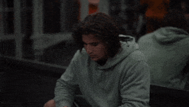 a man in a green hoodie is looking at his cell phone