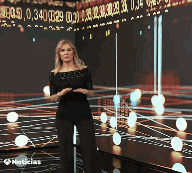 a woman stands in front of a screen that says noticias on it