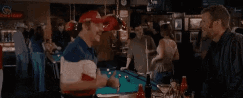 a group of men are playing pool in a bar .