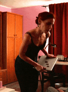 a woman in a black tank top is standing next to a laptop