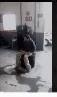 a man is sitting on a barrel in a garage with a sign on the wall that says exit