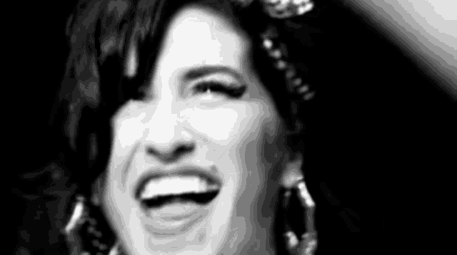 a black and white photo of a woman wearing earrings and smiling .