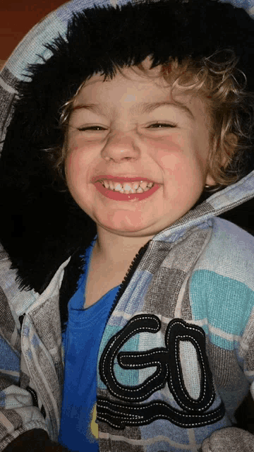 a young boy wearing a jacket with the letter go on the sleeve