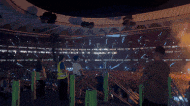 a crowd of people watching a fireworks display in a large stadium