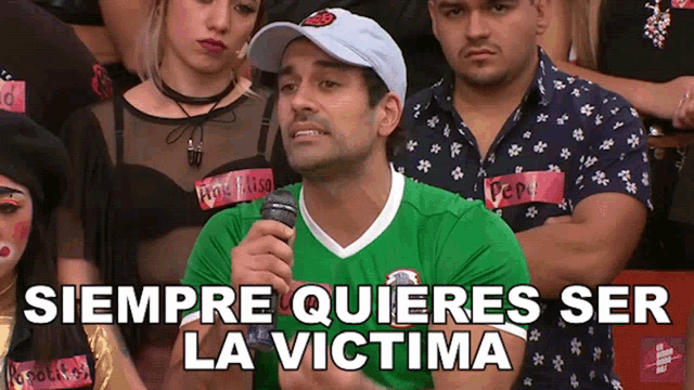 a man in a green shirt is speaking into a microphone with siempre quieres ser la victima written above him