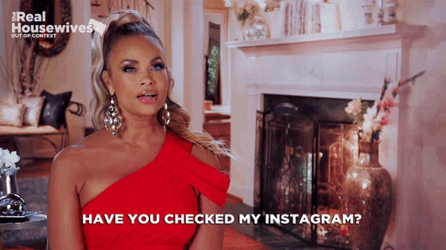 a woman in a red dress says " have you checked my instagram " in front of a fireplace