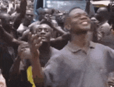 a man is standing in front of a crowd of people holding their hands up in the air .