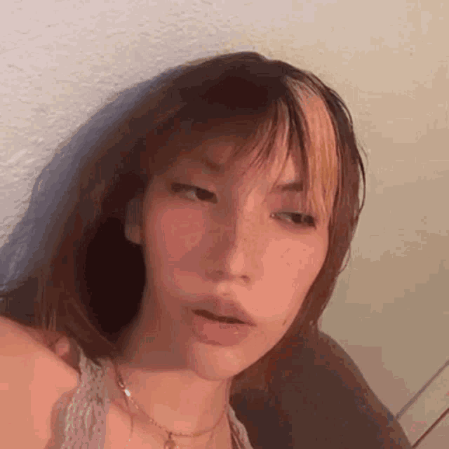 a close up of a woman 's face with a necklace and a fringe .