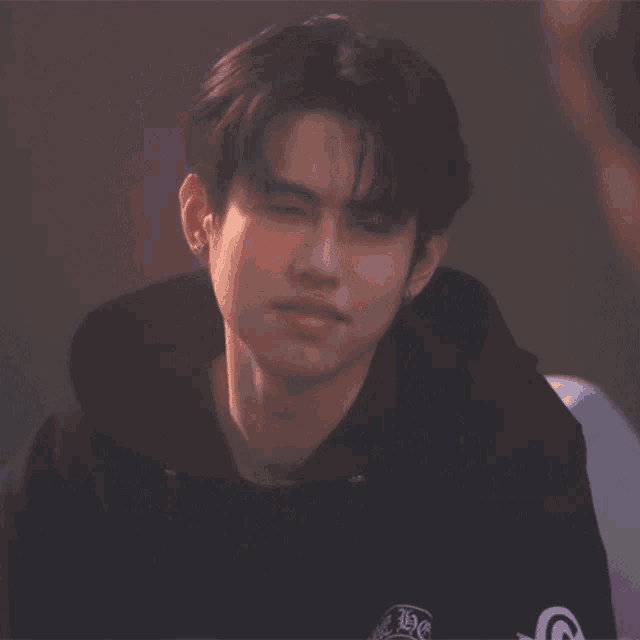 a young man wearing a black hoodie with the letter g on the front