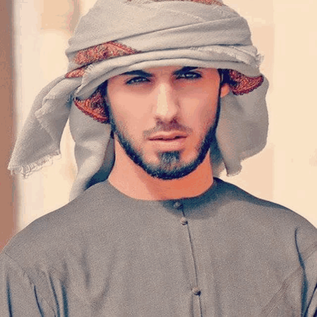 a man with a beard is wearing a scarf around his head and talking on a cell phone .