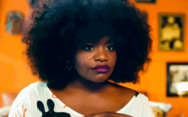 a woman with a large afro is wearing a white shirt with a black paw print on it