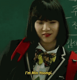 a girl in a school uniform is standing in front of a blackboard and saying `` i 'm min yoongi . ''