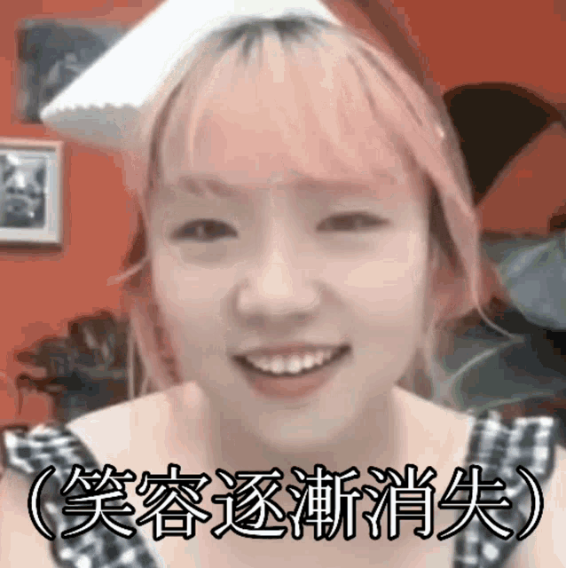 a young girl with pink hair is smiling and wearing a cat ear hat .