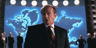 a man in a suit and tie is standing in front of a large screen with a map of the world on it .