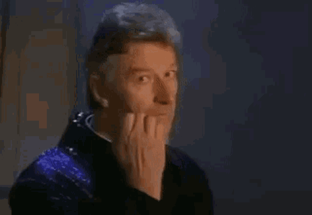 a man is covering his mouth with his hand while looking at the camera .