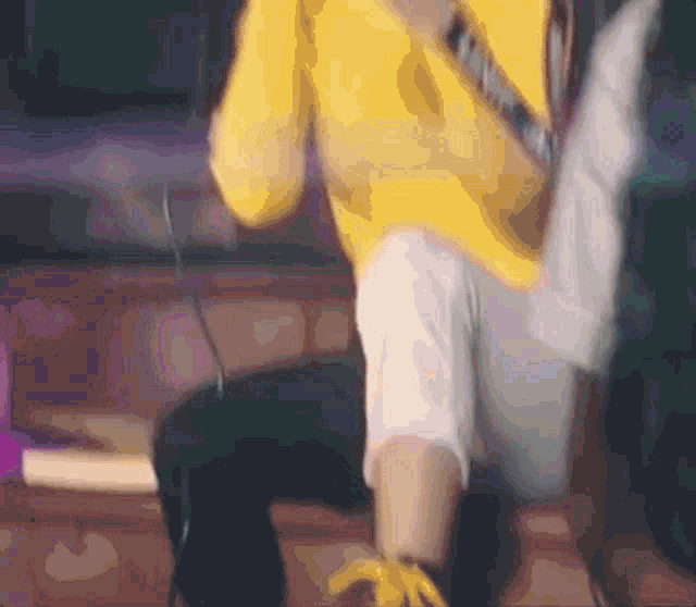 a person wearing a yellow sweater and white pants is kneeling down
