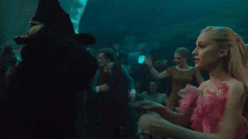 a woman in a green witch costume is hugging another woman