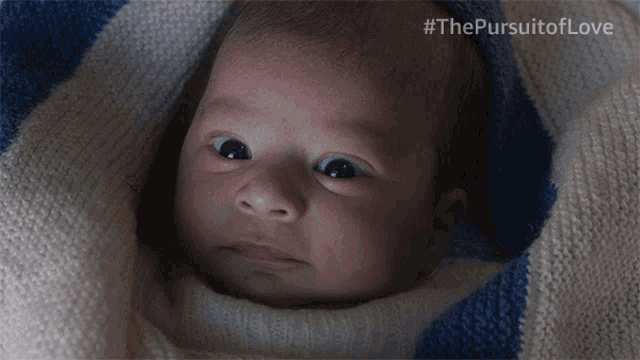 a baby is wrapped in a blue and white striped blanket with #thepursuitoflove written on the bottom