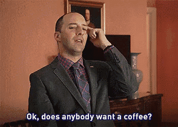a man in a suit and tie is asking if anyone wants a coffee