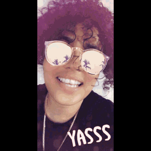 a woman wearing sunglasses and a shirt that says yasss on it