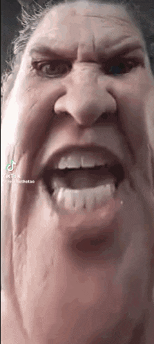 a close up of a woman 's face with her mouth open and teeth visible .