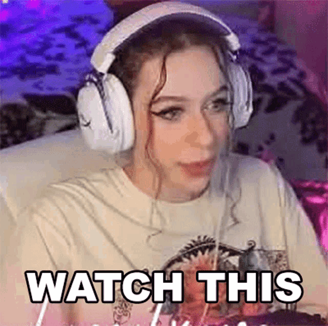 a woman wearing headphones is sitting on a couch with the words `` watch this '' written on her face .