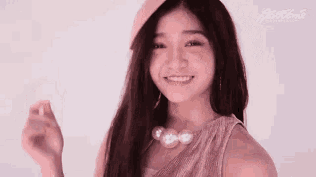 a young woman wearing a hat and a necklace is smiling and looking at the camera .