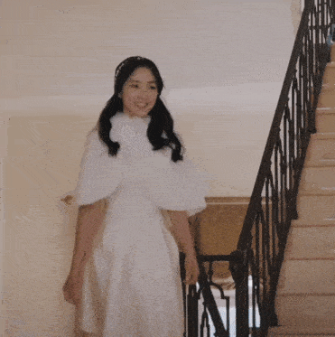 a woman in a white dress with the letter n on her head