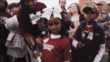 a little girl wearing a mississippi state jersey stands in a crowd