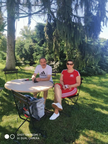 a man wearing an adidas shirt sits next to a woman