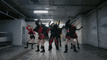 a group of women are dancing in a hallway with a sign on the wall that says " han "