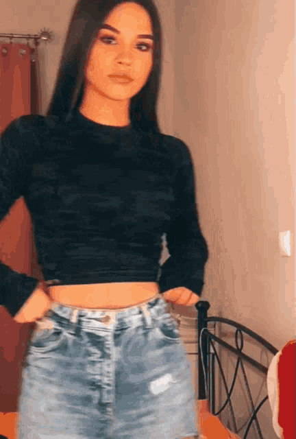 a woman wearing a black crop top and denim shorts