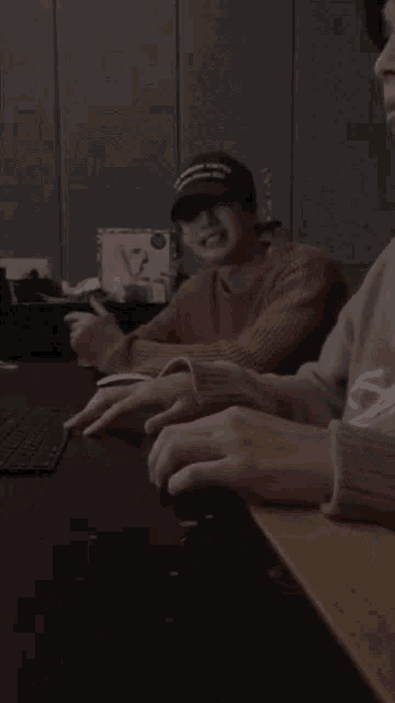 a man wearing a hat that says ' supreme ' on it sits at a desk