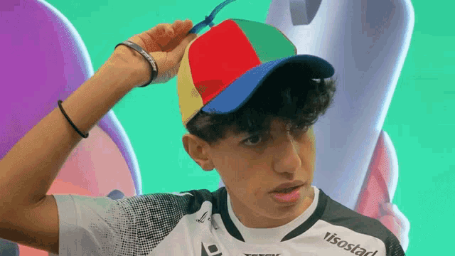 a young man wearing a colorful hat and a shirt that says visostar
