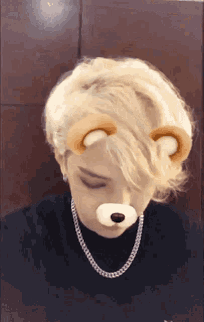 a person wearing a teddy bear face mask and a chain around their neck