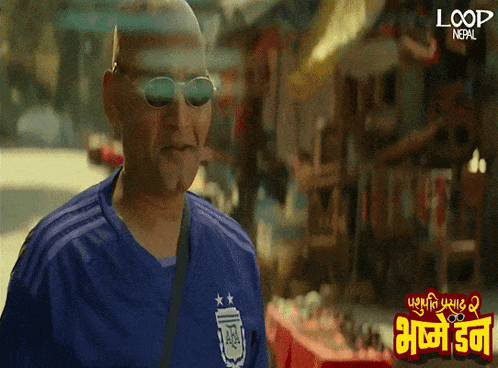a man wearing sunglasses and a blue shirt that says loop nepal on it