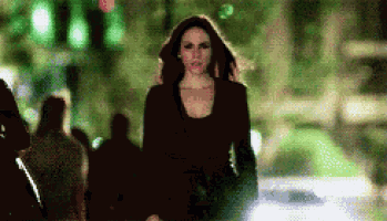 a woman is walking down a street at night in a blurry photo .