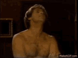 a shirtless man is sitting in a dark room with his shirt off .