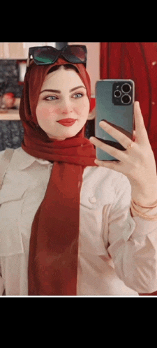 a woman wearing a red scarf takes a selfie with her phone