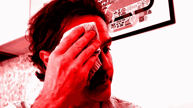 a man wipes his face with a towel in front of a picture of a house