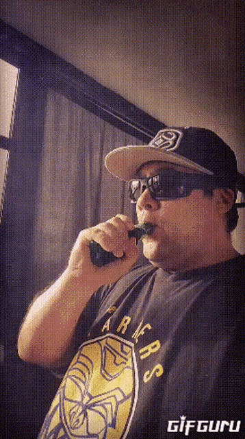 a man wearing sunglasses and a hat is smoking a green cigarette