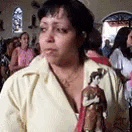 a woman in a yellow shirt is holding a statue of jesus in a church .