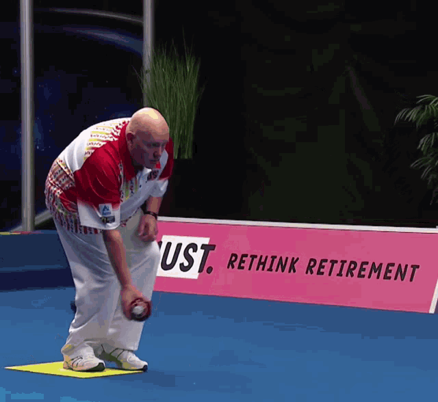 a man throws a ball in front of a sign that says ust