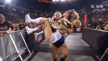 a wrestler is carrying another wrestler in his arms during a match