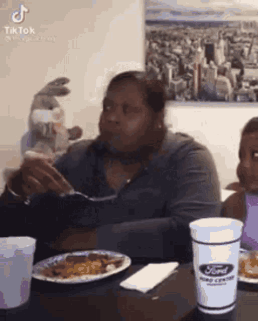 a woman is sitting at a table eating food and drinking a cup of coffee .